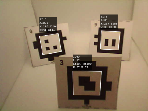 Three square cards with AprilTags being tracked by a vision system. Each card is labeled with an ID number and associated tracking data. The card on the left is labeled ID:0, showing coordinates A:350°, X:110, Y:96, W:41, H:41. The middle card, labeled ID:3, has coordinates A:1°, X:187, Y:180, W:57, H:57. The card on the right is labeled ID:9, with coordinates A:3°, X:237, Y:89, W:38, H:38. Each card has a white outline, and the system is tracking their positions and orientations.