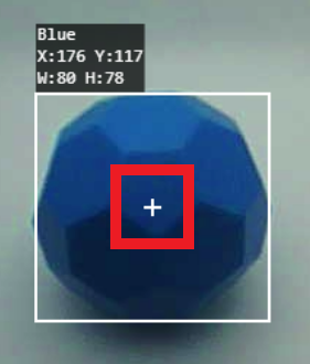 Egy kék Buckyballt egy számítógépes látórendszer követ. Az objektumot egy fehér négyzet körvonalazza, a körvonalon belül pedig egy kisebb piros négyzet, amely egy középen fehér keresztet vesz körül. A kép bal felső sarkában egy címke jelzi, hogy az objektum kék színű, X:176, Y:117 koordinátákkal és W:80, H:78 méretekkel.