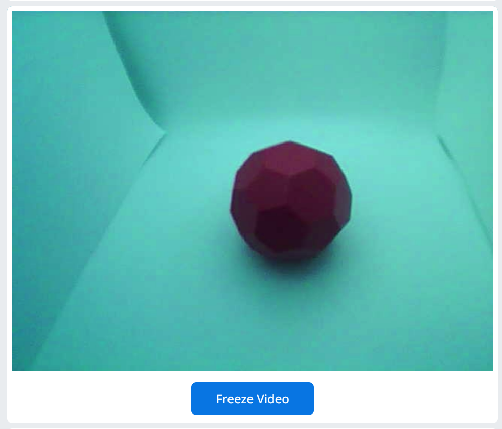 Se muestra la transmisión de video de AI Vision Utility y un Buckyball rojo está en la vista del sensor. El video tiene un tinte azul verdoso y el Buckyball rojo aparece más gris debido al tinte.