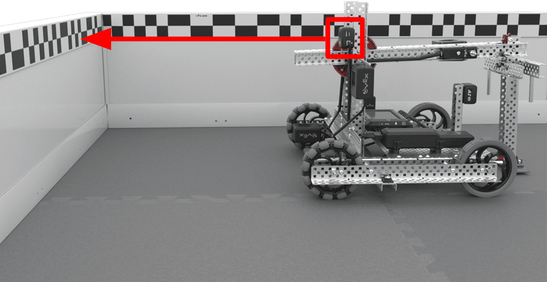 Axel tyhjällä kentällä nurkassa, GPS-sensori asennettuna robotin takaosaan kentän reunalla olevaa kenttäkoodia päin. Siellä on punainen laatikko, joka korostaa GPS-anturin sijaintia robotissa ja ja nuoli, joka kuvaa anturin kohdistusta kenttäkoodiin.