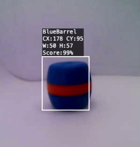 Ein blaues Fass, das von einem Sichtsystem verfolgt wird. Ein weißer Umriss umgibt das Objekt, mit einem zentrierten weißen Kreuz innerhalb des Umrisses. Das Etikett oben links gibt an, dass es sich bei dem Objekt um ein blaues Fass handelt, zusammen mit den Mittelpunktskoordinaten CX:178, CY:95 und den Abmessungen B:50, H:57.