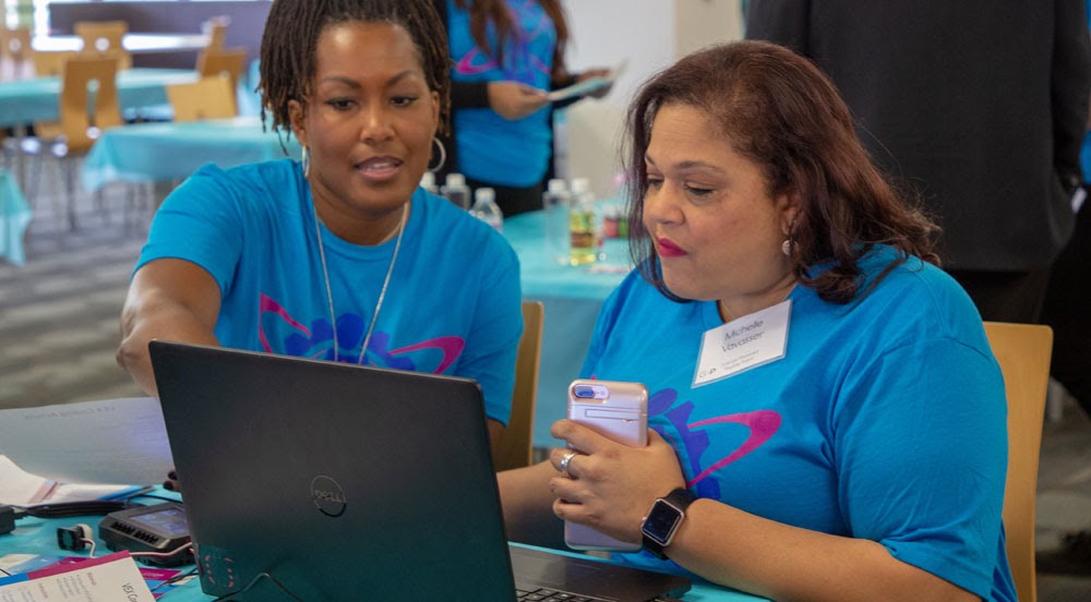 A classroom scene featuring educators engaging with a computer planning their lessons together, illustrating the collaboration teachers can have as well across the continuum.