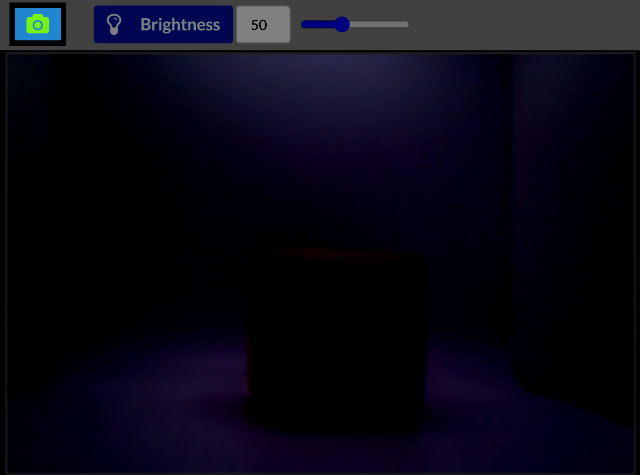 A dim Vision Sensor preview showing a barely visible red cube due to low lighting. The brightness control at the top is set to 50. The object is mostly in shadow, with the background appearing dark purple.
