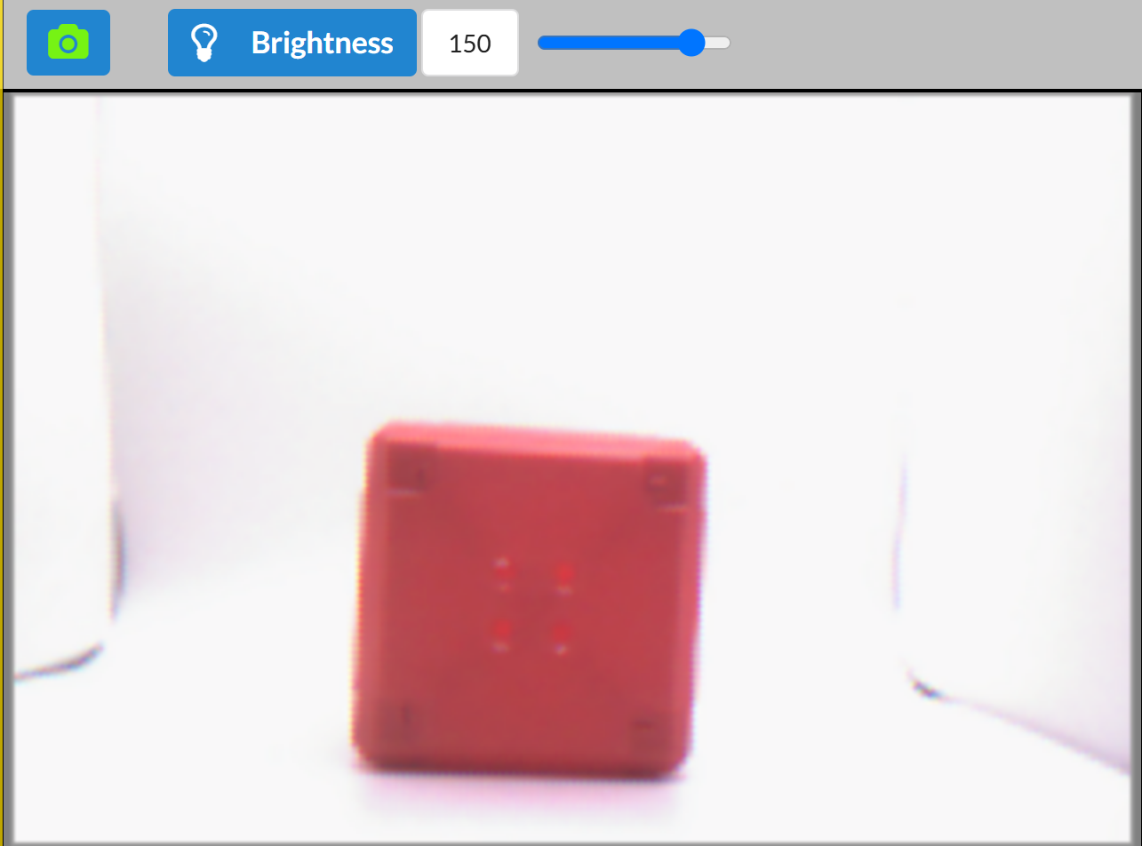 The Vision Sensor preview with brightness increased to 150. The red cube is centered and brightly lit, but the image appears overexposed with washed-out colors. Details of the cube are difficult to discern due to the intensity of the lighting.