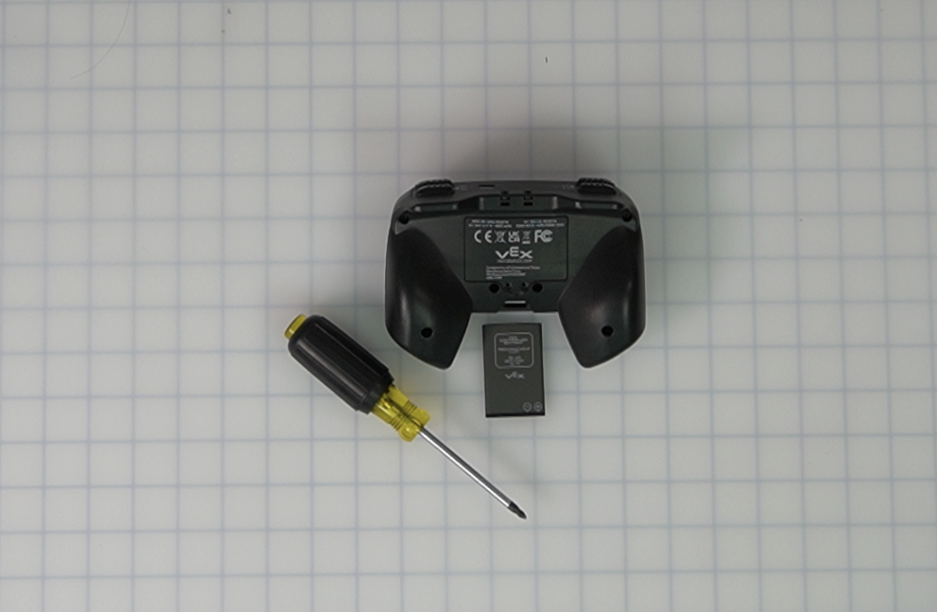 EXP Controller, EXP Controller Battery, and a Phillips screwdriver placed together on a table.
