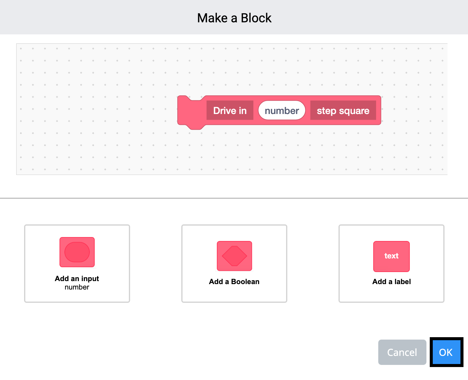 เมนู Make a Block ของ VEXcode 123 เปิดอยู่และมีการสร้างบล็อกแบบกำหนดเองแล้ว บล็อกนี้จะอ่านว่า Drive in ก่อน จากนั้นจะมีช่องสำหรับป้อนตัวเลข และจะจบลงด้วยช่องสี่เหลี่ยมขั้นตอนการอ่านฉลาก เมื่อรวมกันแล้ว บล็อกที่กำหนดเองจะอ่านว่า Drive ในช่องสี่เหลี่ยมขั้น X ปุ่มตกลงสีน้ำเงินที่ด้านล่างขวาถูกเน้นไว้