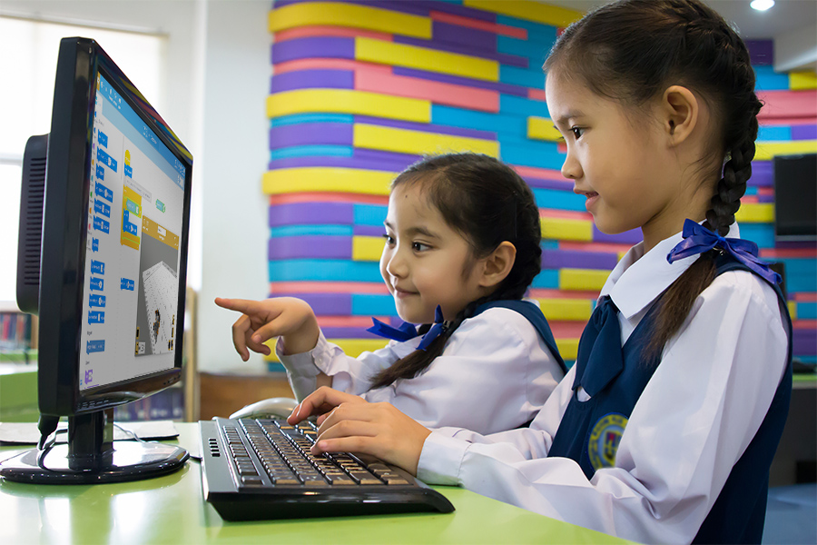 Twee kinderen wijzen enthousiast naar een computerscherm met VEXcode VR, een demonstratie van een leuke educatieve activiteit over programmeren en robotica.