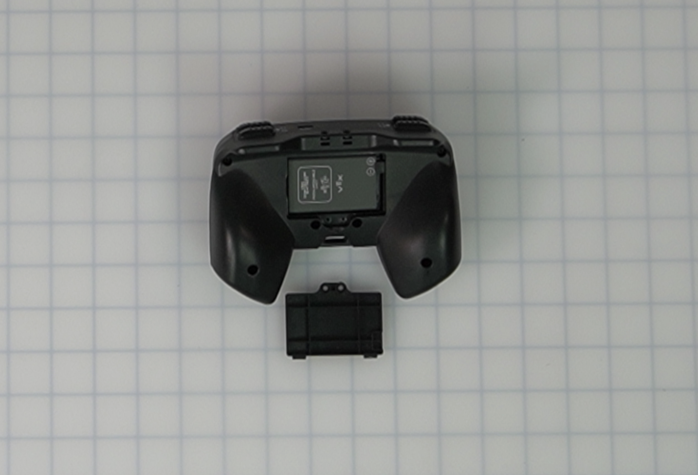 Controller con lo sportello della batteria aperto e una nuova batteria inserita. La batteria presenta delle icone positive e negative che devono essere allineate con quelle presenti sul Controller. In questa immagine le icone della batteria si trovano nell'angolo in alto a destra dello slot della batteria.