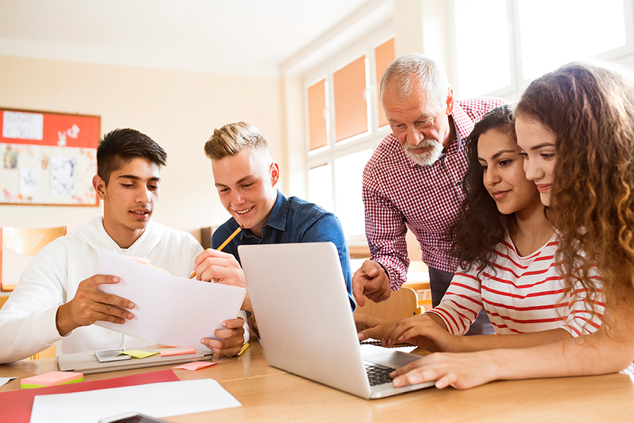 Een groep studenten bespreekt met hun docent de pseudocodeopdracht.