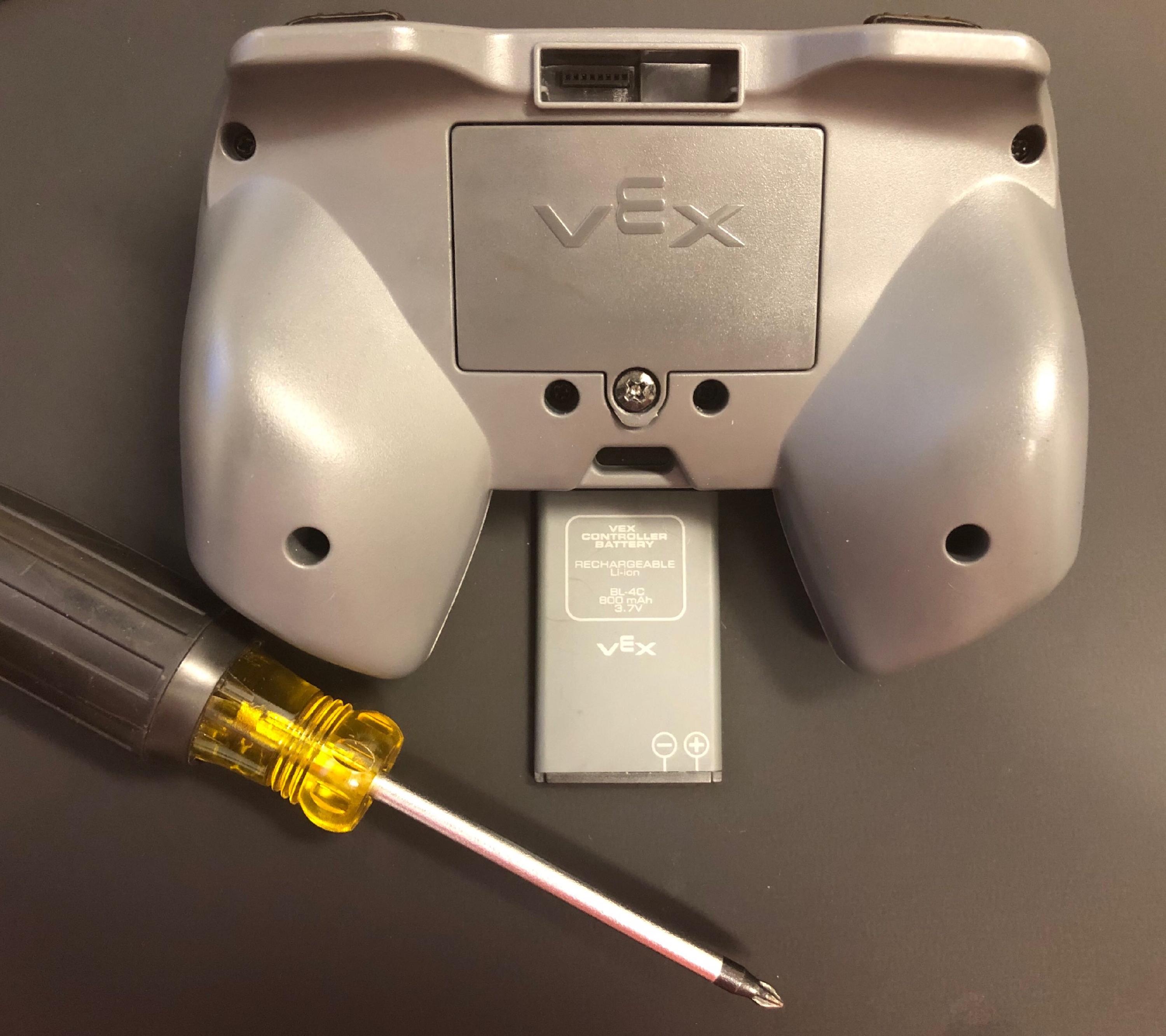 IQ Controller, IQ Controller Batterij en een kruiskopschroevendraaier liggen samen op een tafel.