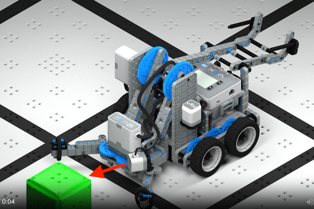 Clawbot IQ rakentaa pellolla ajamista, ja nuoli osoittaa kiinnitetystä värisensorista robotin edessä olevaan vihreään kuutioon.