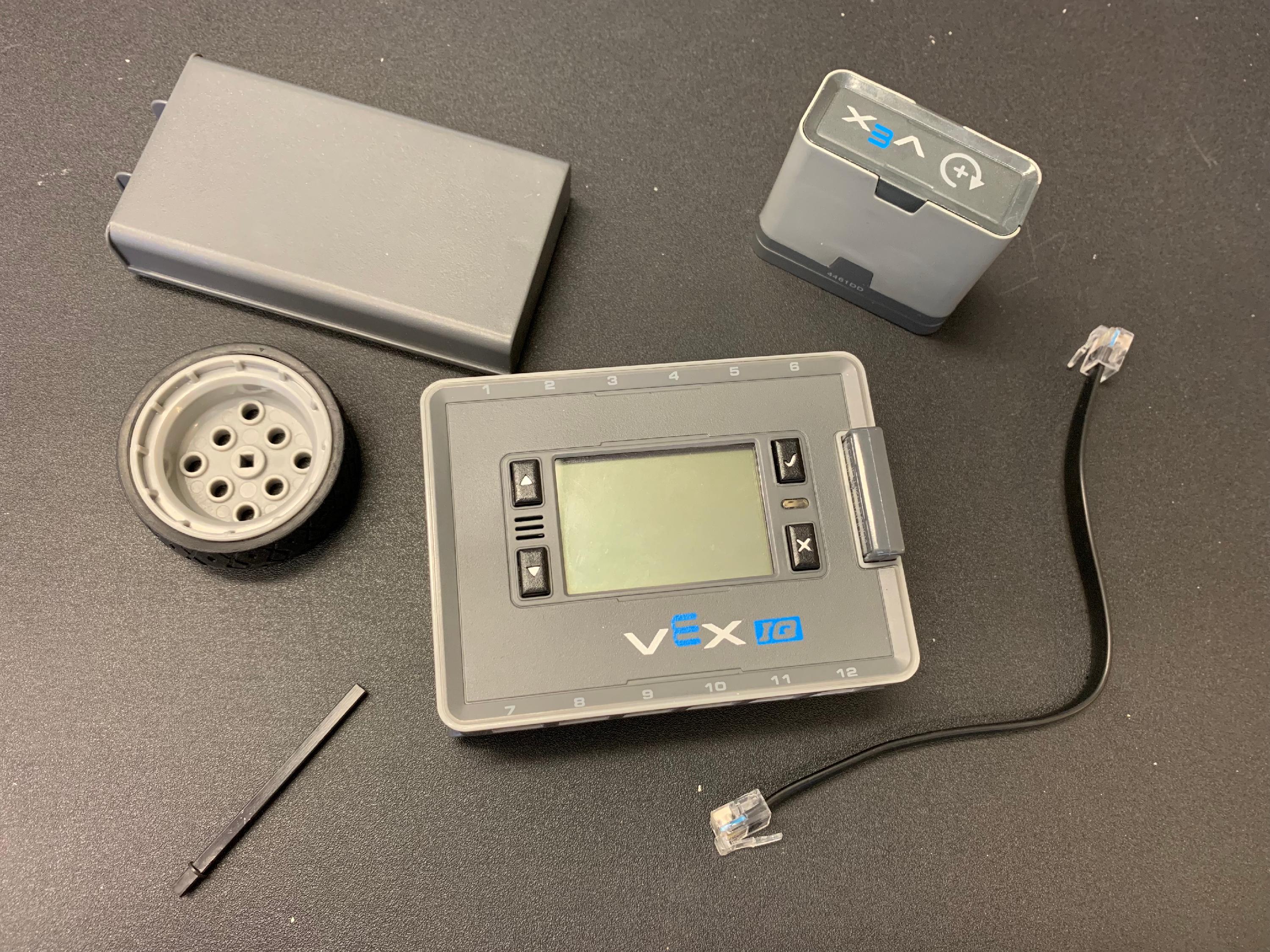 Un moteur intelligent, un arbre moteur, un cerveau IQ, une batterie IQ, un câble intelligent et une roue placés ensemble sur une table.