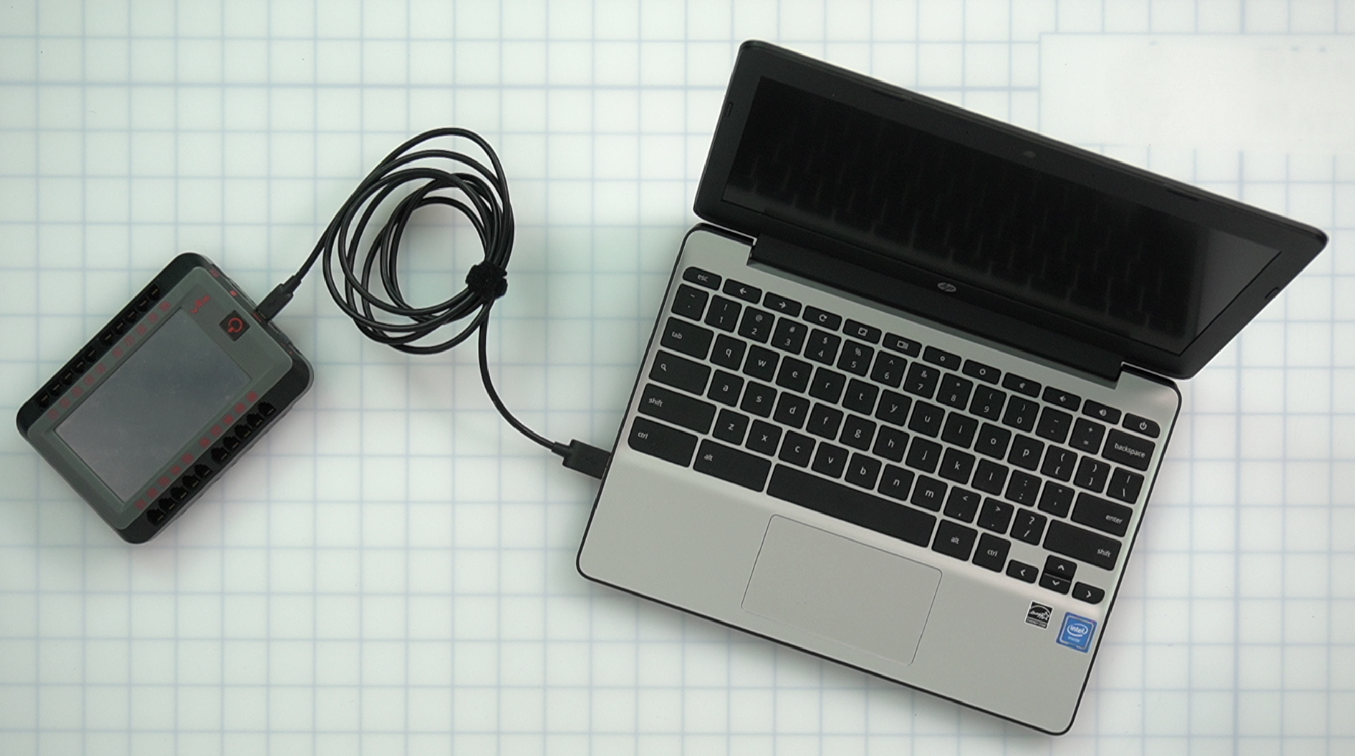 V5-Chromebook an eine Stromquelle angeschlossen, mit Ladeanzeige auf dem Bildschirm, die den Verbindungsvorgang mit dem Gehirn im V5-Robotiksystem veranschaulicht.