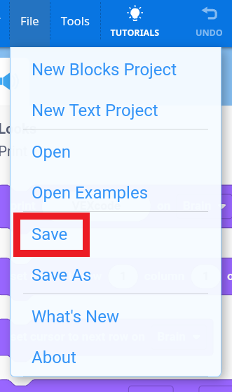 Menu tarik-turun dari antarmuka VEXcode yang menampilkan opsi di bawah tab File, dengan opsi Simpan disorot oleh kotak merah. Pilihan lain yang terlihat meliputi Proyek Blok Baru, Proyek Teks Baru, Buka, Buka Contoh, Simpan Sebagai, Apa yang Baru, dan Tentang.