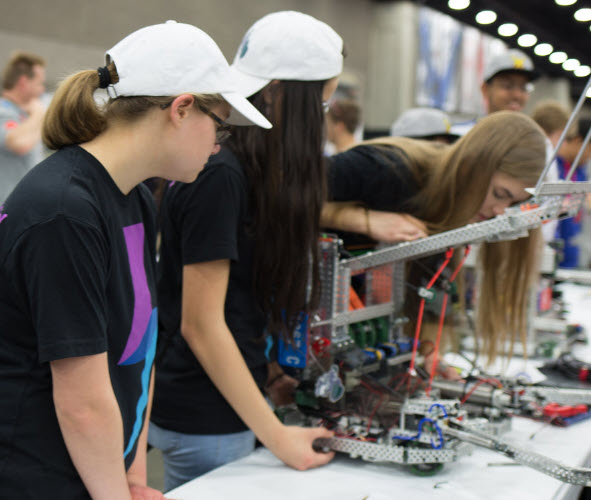 A group of students are working together to assemble a V5 robot in a classroom environment.