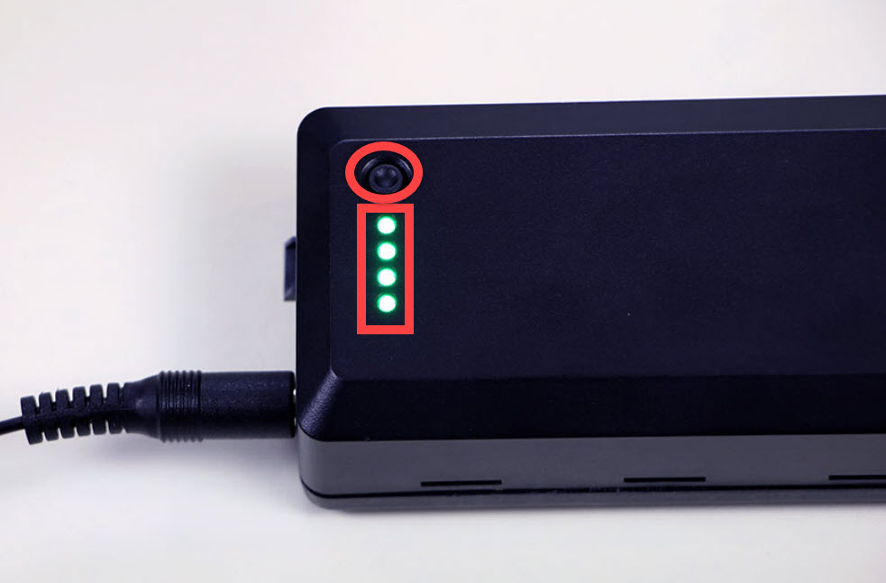 Charging V5 Robot Battery is shown with its push button and 4 LED indicator lights highlighted. The push button is next to the indicator lights, and in this example all 4 lights are glowing which indicates that the Battery is fully charged.