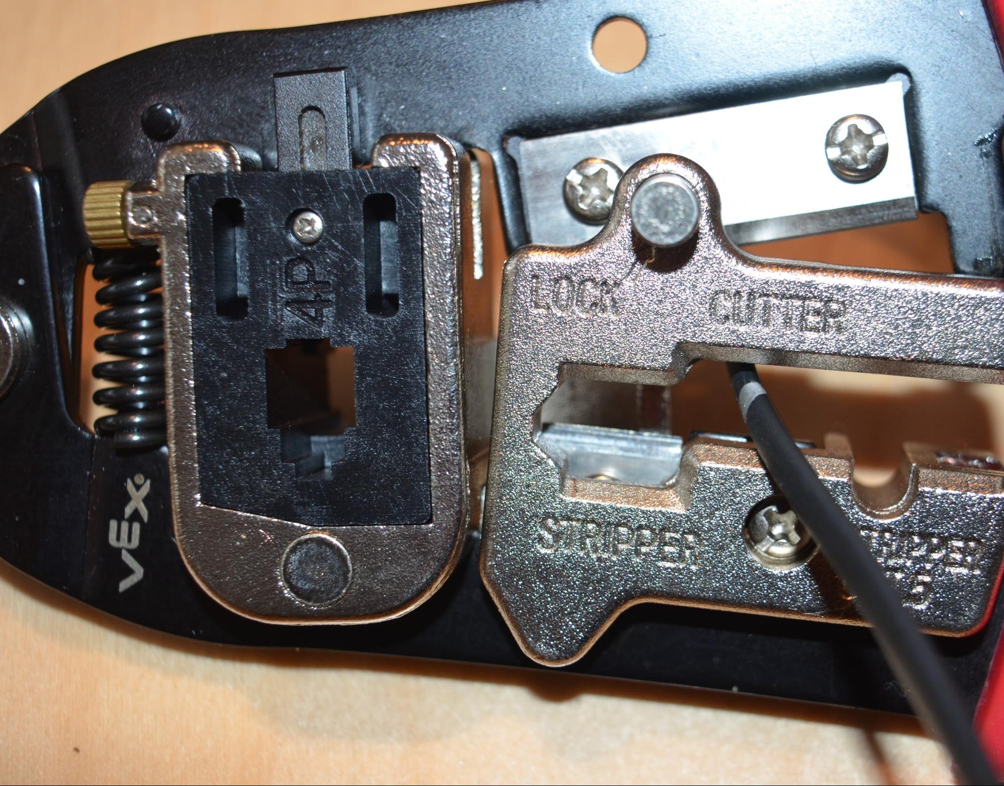 V5 Cable is placed into the cutting section of the crimping tool up to the cable's marked length. Once the cable is in place, the handles can be squeezed to cut through the cable.