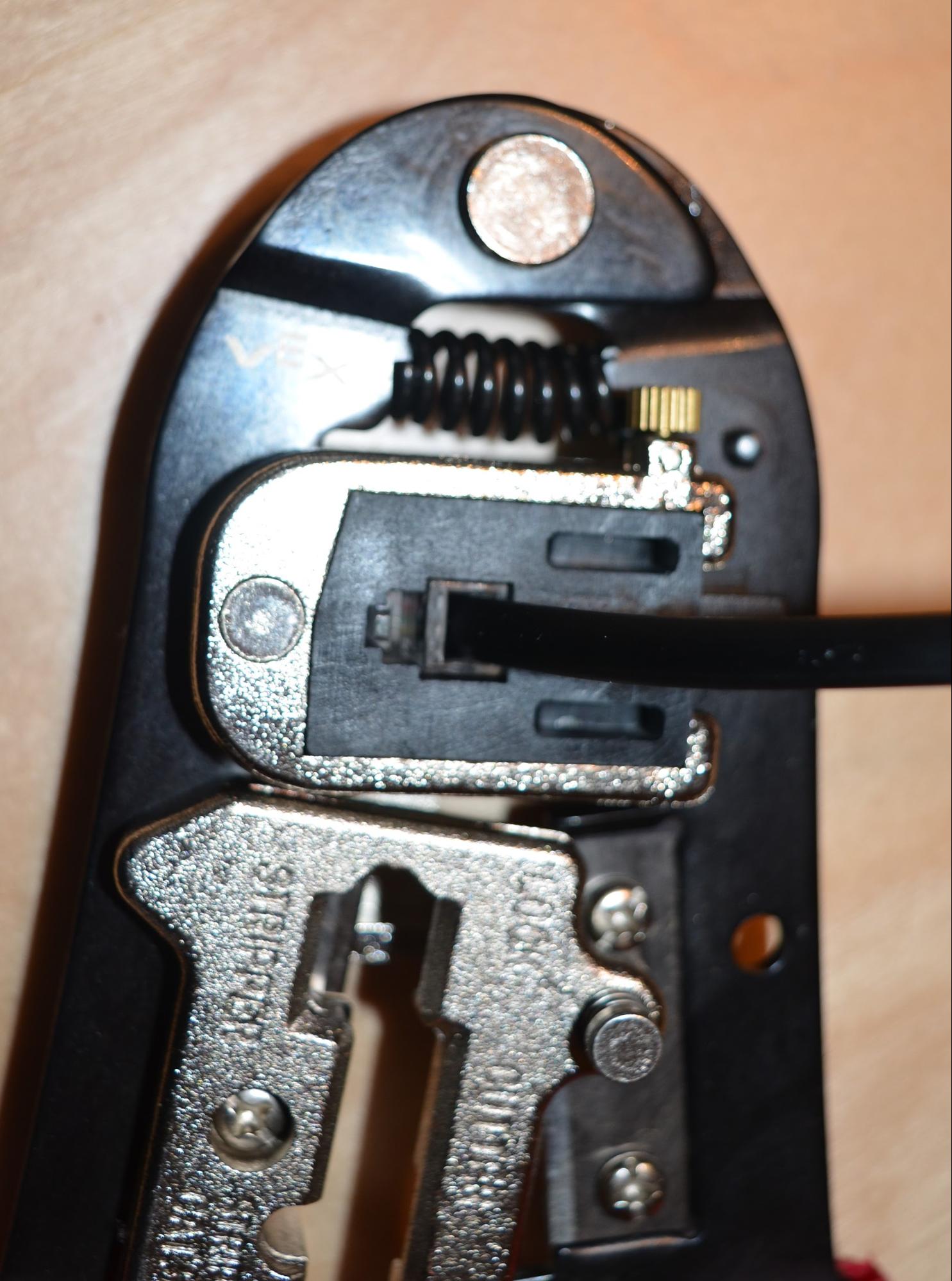 Top down view of a cable connector placed into the crimping section of the crimping tool.