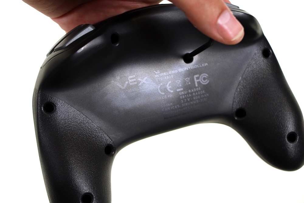 One end of a hex key is shown being pressed into the reset button to reset the V5 Controller.