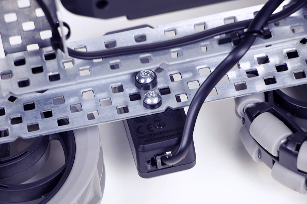 Close up of a mounted V5 Robot Radio, with both of the screws in place to keep it secure. In this example, each screw has a Plastic Spacer piece. There is also a Smart Cable connected to the Robot Radio's port to connect it to the V5 Brain.