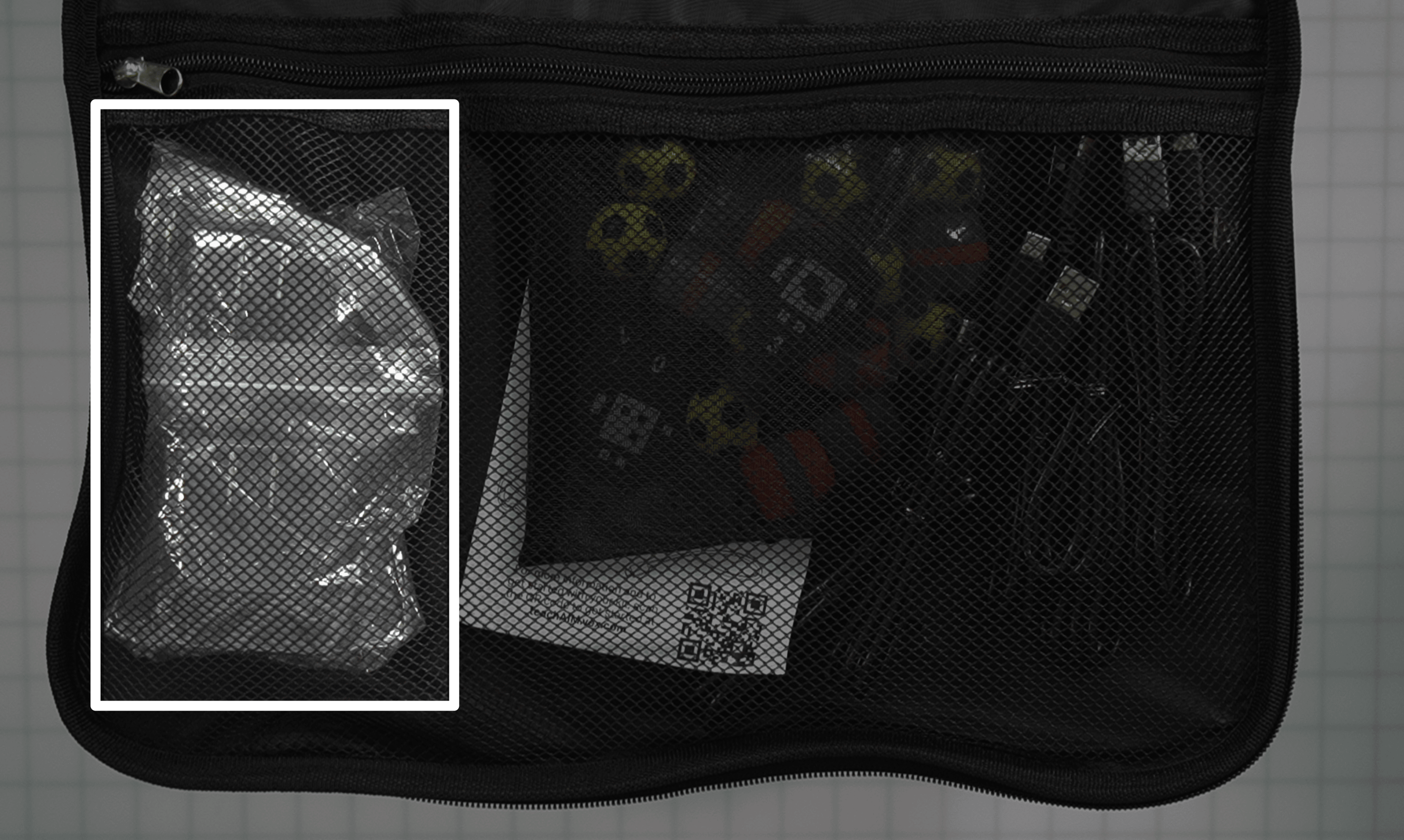 Užtrauktuku užsegamo skyriaus ant maišo dangtelio vaizdas iš viršaus. USB 4 krypčių įkrovikliai yra paryškinti kairėje pusėje, siauroje užtrauktuku užsegamos kišenės dalyje.