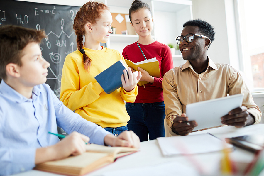 A group of students with their teacher discussing the pseudocode assignment.