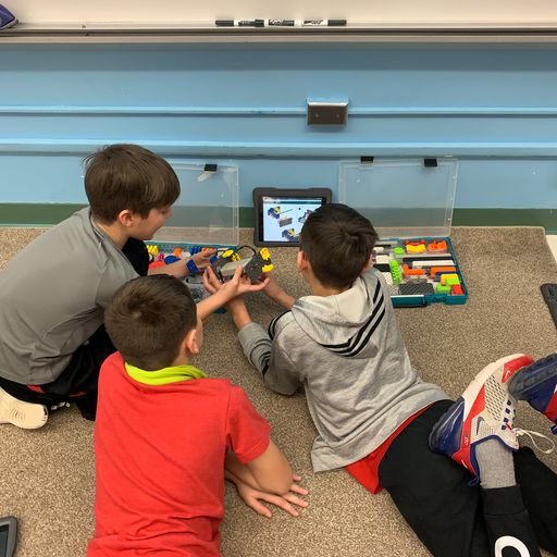 Three students work on the floor to construct a VEX GO robot.