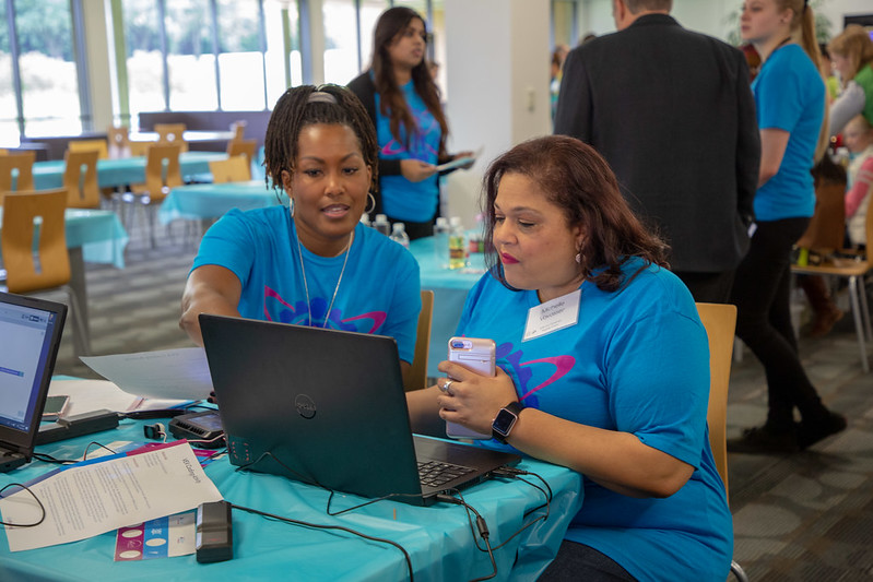 Two educators work together at a workshop, in the midst of others in a classroom setting.