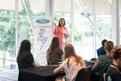 A female guest speaker addresses a room full of young girls at a Girl Powered event.