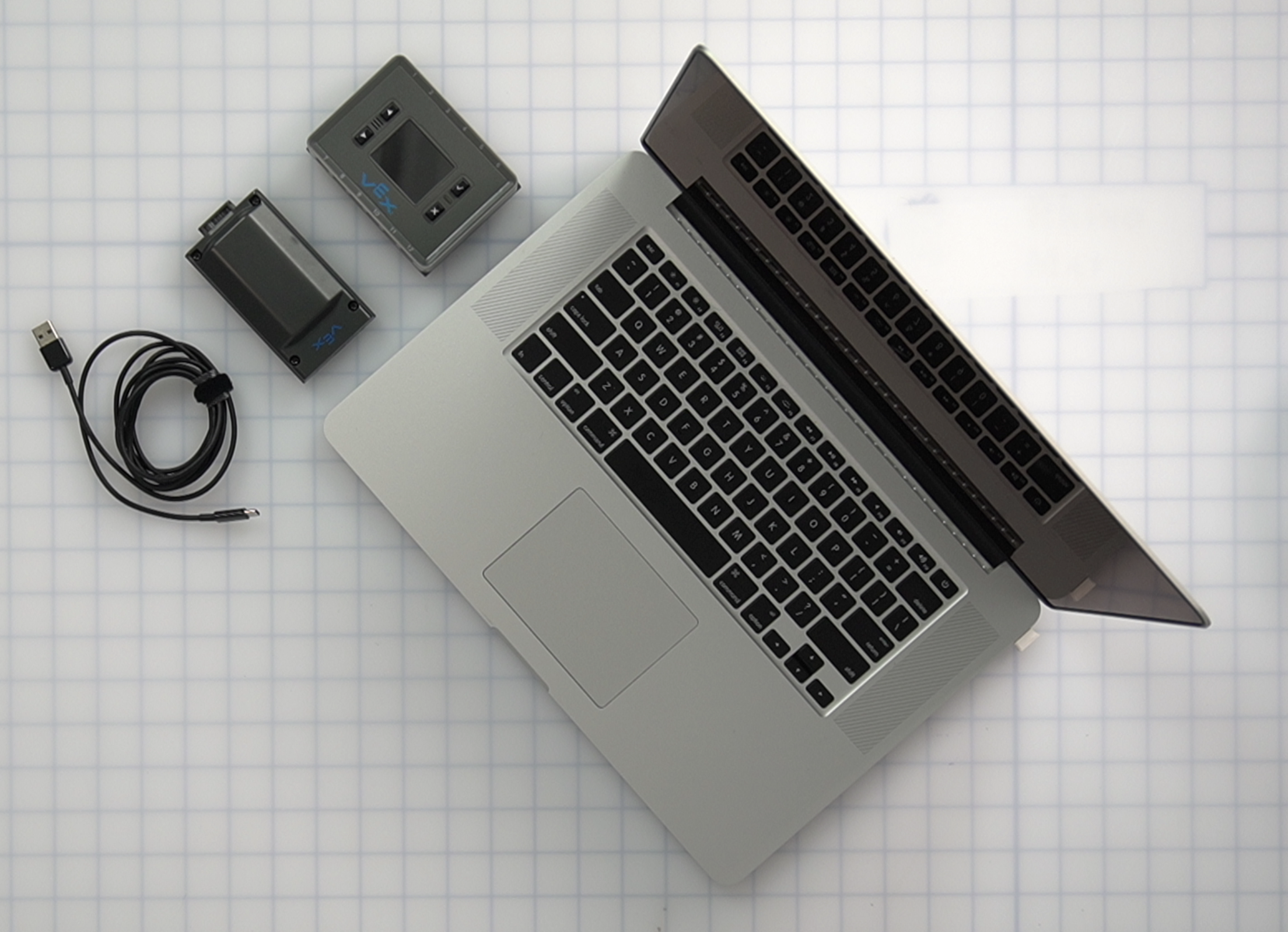 Εγκέφαλος, μπαταρία, καλώδιο USB και ένα λάπτοπ τοποθετημένα τακτοποιημένα μαζί σε ένα τραπέζι.