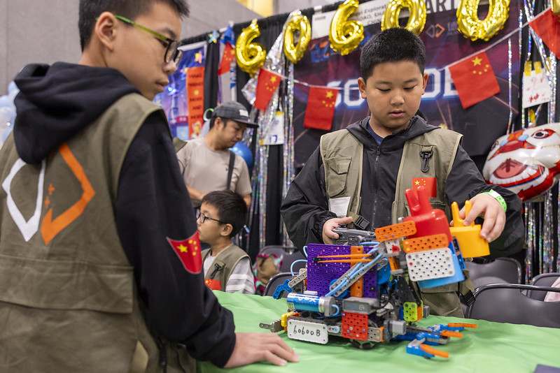 Dua siswa bekerja sama membuat robot plastik VEX IQ.